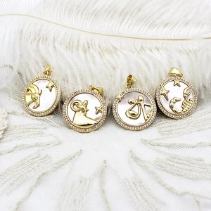 Detailed close-up of 18K gold-plated zodiac pendants with white shell and inlaid crystals