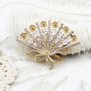 Detail of fan-shaped brooch with white zircons and bow design on lace background