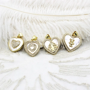 Detail of 18K gold heart charms with mother of pearl and bear inlay on white lace