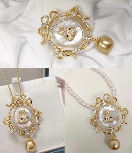 Vintage rabbit brooch with gold frame, shimmering shell base and hanging golden pearl