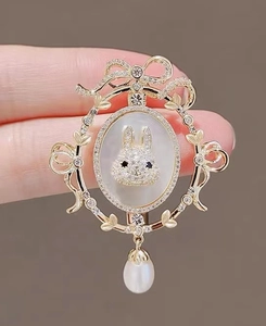 Detail of luxury rabbit brooch with crystal frame and drop pearl hanging from a gold base