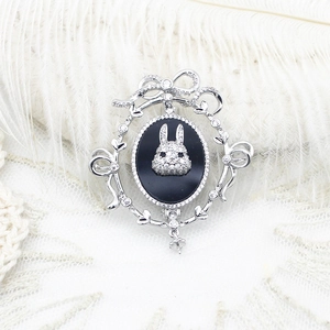 Elegant silver rabbit brooch with black oval gem and micro-set diamonds on lace fabric