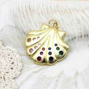 Detalle del colgante de concha chapado en oro con pedrería de colores y textura