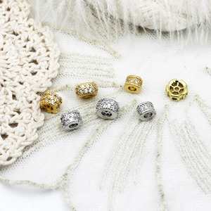 Detalle de cuentas espaciadoras cilíndricas bañadas en oro de 18K con circonitas