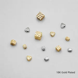 Macro shot of 18K gold plated copper beads with square and triangle textured patterns