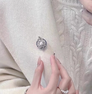 Detail showing the dragon-shaped 18K gold-plated brooch pinned on a knitted coat