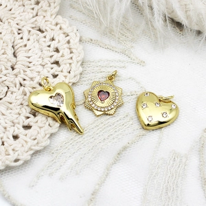 Detailed view of 18K gold plated heart pendants with zircon stones and sunburst design