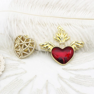 Detail of 18K gold plated heart charms with red enamel wings and crystal mesh textures