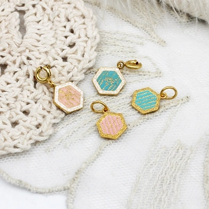 Nahaufnahme hexagonaler Schmetterlingsanhänger mit goldenem Metallrand und Emaille-Details