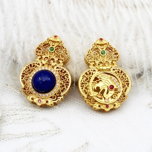 Macro detail of golden hollow gourd pendant with blue gemstone and phoenix carving