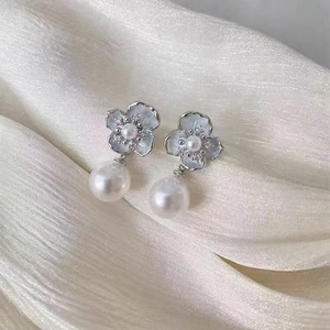 Detailed close-up of shell petal flower earrings with pearls and zircon on silk