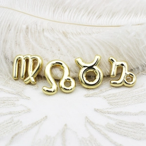 Detailaufnahme goldener Sternzeichen-Anhänger für DIY-Schmuck auf weißer Feder