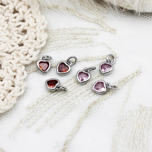 Macro detail of six mini silver-plated heart pendants with red and pink cubic zirconia gems