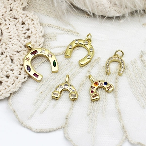 Macro detail of 18K gold plated horseshoe and rainbow pendants with colorful zircon stones
