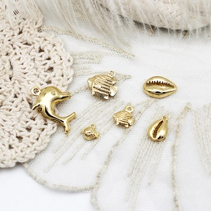 Macro view of ocean themed 18K gold plated charms including dolphin and shells