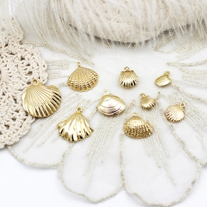 Detailed view of 18K gold-plated starfish and seashell pendants on white lace fabric