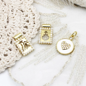 Close-up of 18K gold plated charms with pearls and rhinestones in religious and heart motifs