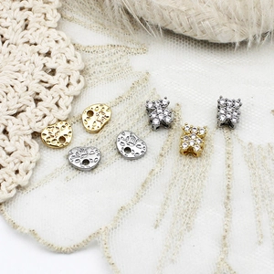 Detailaufnahme von vergoldeten Bärenanhängern und gravierten Perlen für DIY-Schmuck