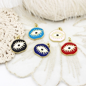 Detail of colorful evil eye pendants in gold alloy on white lace and feather background
