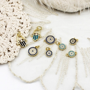 Detail of Hamsa Hand and Evil Eye gold plated charms with blue rhinestones and enamel