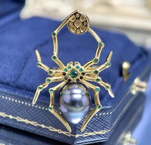 Macro-opname van 18K gouden spinnenbroche met zwarte Tahiti-parel en groene edelstenen