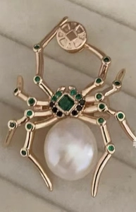 Detail van 18K vergulde spinnenbroche met een witte parel en groene edelstenen