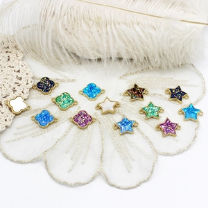 Detailed view of 18K gold plated clover and star pendants with iridescent resin inlay