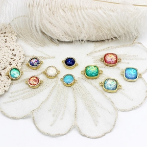 Macro detail of 18K gold plated charms with colorful resin stones and connector rings