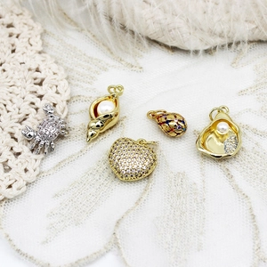 Detailed view of micro-paved sea shell and crab pendants for DIY jewelry making