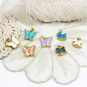 Detailed view of colorful butterfly and rocking horse charms in 18K gold plated metal