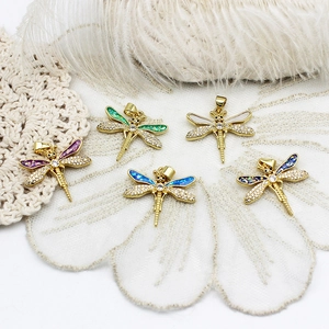 Detailed macro view of gold dragonfly pendants with colorful opal wings and sparkling zircon