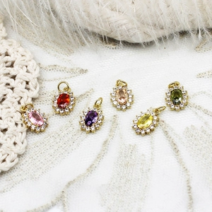 Macro shot of oval colored gemstones with zircon halos on elegant lace and feather background