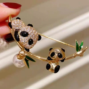 Détail de la broche panda avec feuilles de bambou et pendentif en perle blanche