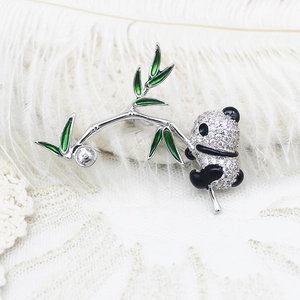Détail macro d'une broche panda avec feuilles de bambou émaillées et zircons sertis