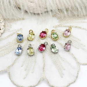 Pendenti colorati in zirconia marquise con basi in oro e argento su sfondo di pizzo