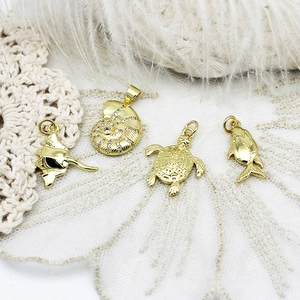 Detailed close-up of 18K gold marine pendants featuring stingray, nautilus and turtle charms