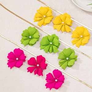 Close-up of matte metal flower pendants in yellow, green and pink with pearl centers