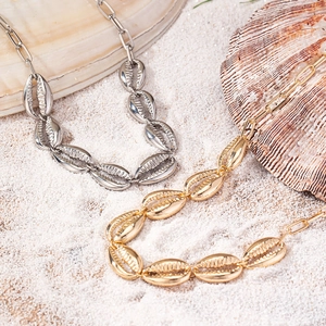 Dettaglio della collana con ciondolo a conchiglia in oro e argento su sabbia bianca
