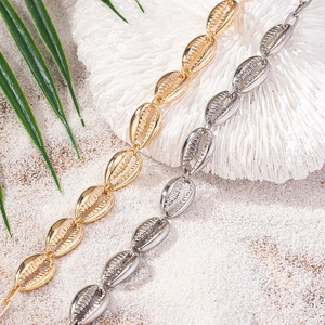 Collane con ciondoli a conchiglia oro e argento presentate su sabbia e pietre naturali