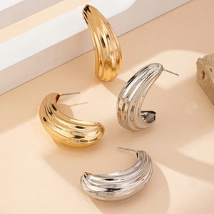 Detail van C-vormige metalen oorbellen in shrimp-stijl met goud en zilveren textuur