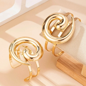 Dettaglio di bracciali a spirale dorati con design a tre barre su supporto per gioielli