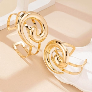 Set di bracciali a spirale in oro lucido con design artistico traforato su sfondo neutro