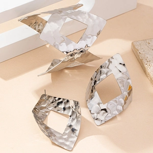 Dettaglio di un set di gioielli geometrici argento con trama martellata e design traforato