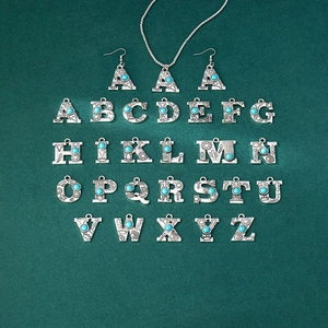Close-up of vintage silver letter pendants with turquoise stones and western engravings