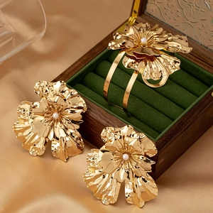 Elegant gold flower jewelry set with pearls on satin background for women
