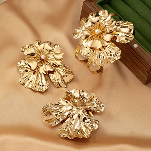 Golden flower jewelry set with pearls including floral earrings and an open bangle