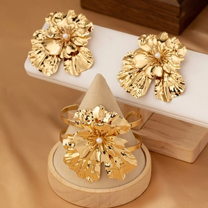 Detailed view of vintage gold flower jewelry set with pearls on silk background