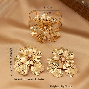 Detail of gold flower jewelry set featuring pearl centers and textured petals