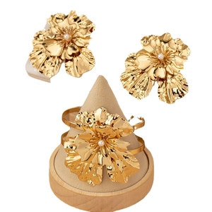 Golden flower jewelry set with pearls featuring textured earrings and open cuff bracelet