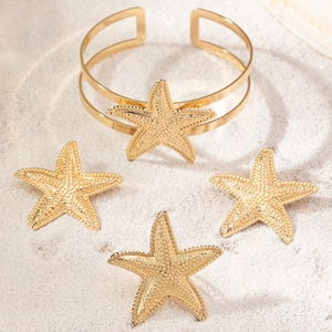 Three-piece golden starfish jewelry set on white sand beach background for women